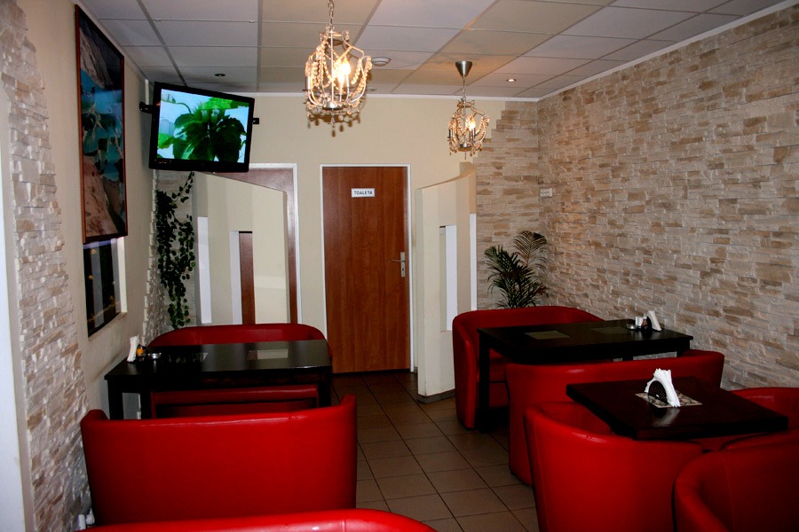 Sala Sila Kebab z czerwonymi kanapami i stolikami